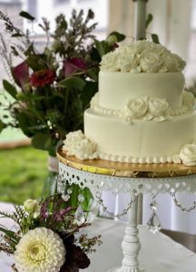 A white wedding cake with flowers on top of it.