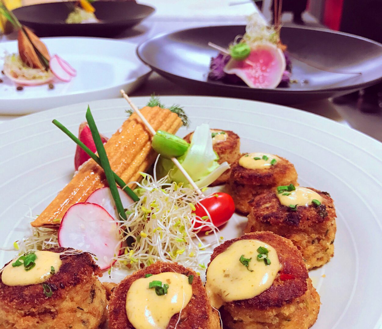 A plate of food with crab cakes and vegetables.