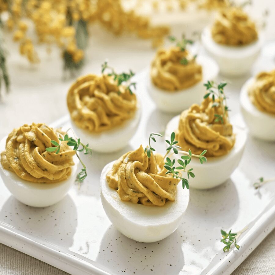 Deviled eggs garnished with fresh herbs.